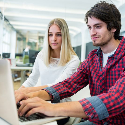 Male and female business executives working on laptop in office